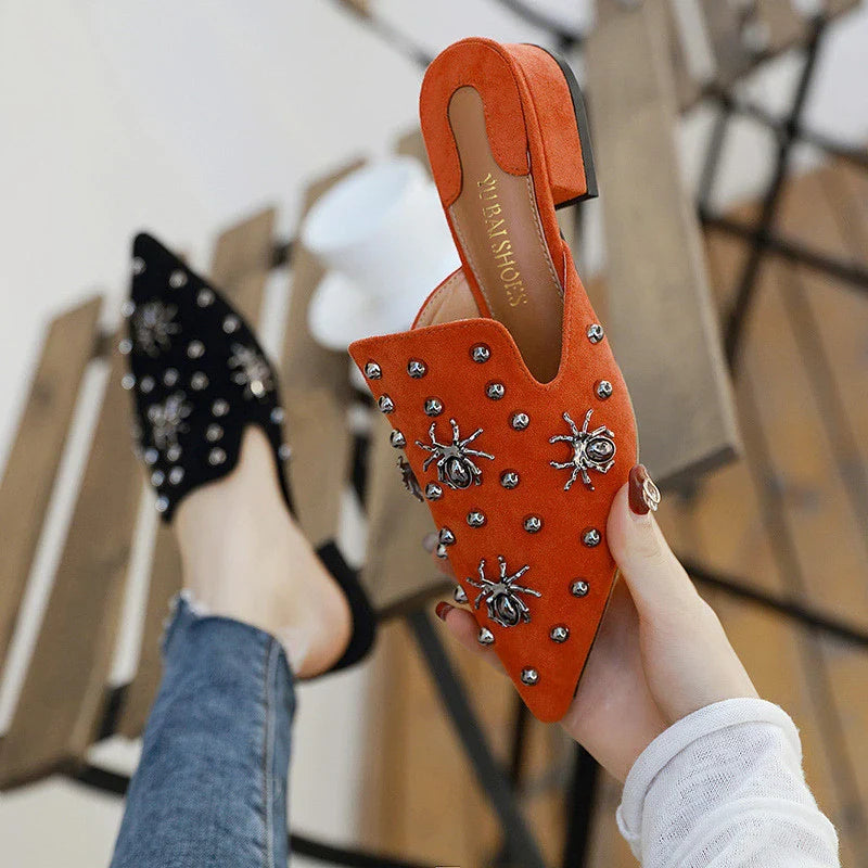 A pair of flat-bottomed, lazy half-slipper style sandals in a sleek, minimalist design with metal accents