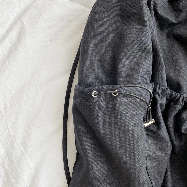 A stylish drawstring bucket bag in white, black, or brown colour options, featuring a spacious interior and adjustable closure for modern British women.