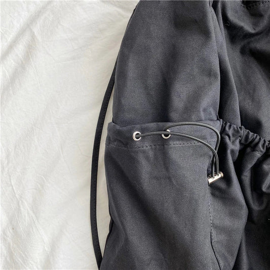 A stylish drawstring bucket bag in white, black, or brown colour options, featuring a spacious interior and adjustable closure for modern British women.