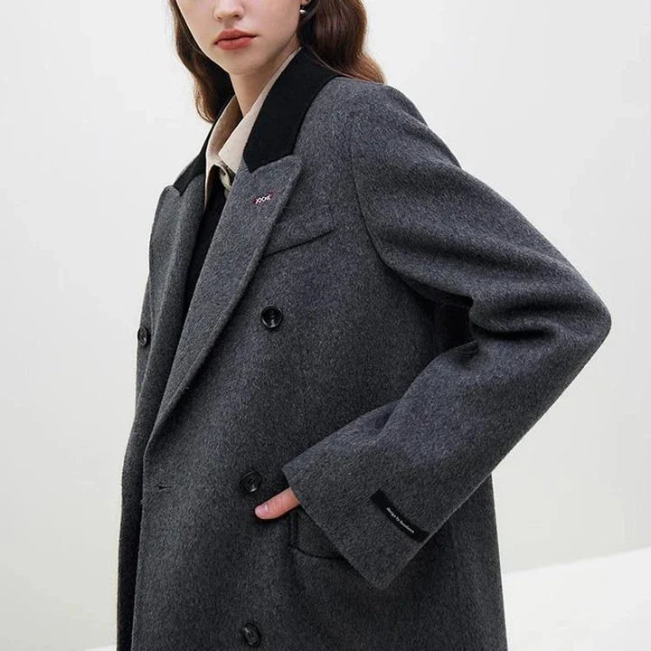 A sophisticated and stylish dark grey woollen coat for women, designed with a timeless double-breasted closure and notched collar.