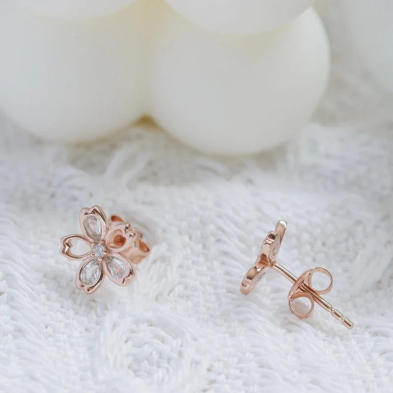 Pair of elegant zircon cherry blossom earrings in skin colour, featuring a delicate floral design and sparkling stones