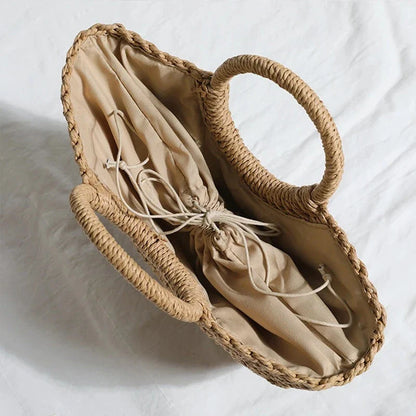 Premium handwoven straw beach tote with a casual half-moon shape and secure string closure, perfect for summer outings