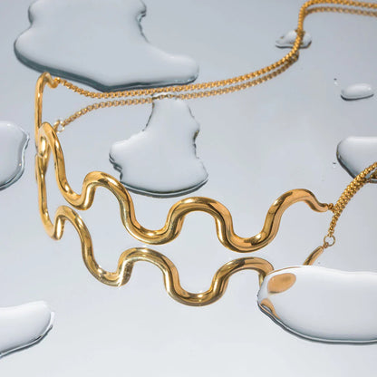 Elegant 18K gold-plated stainless steel wave bracelet and necklace set for women, showcasing a unique contemporary design with adjustable drawstring closure