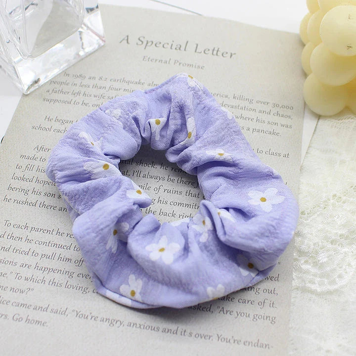 A pair of white hair bands with vibrant, hand-embroidered daisy patterns, providing a stylish and comfortable accessory.