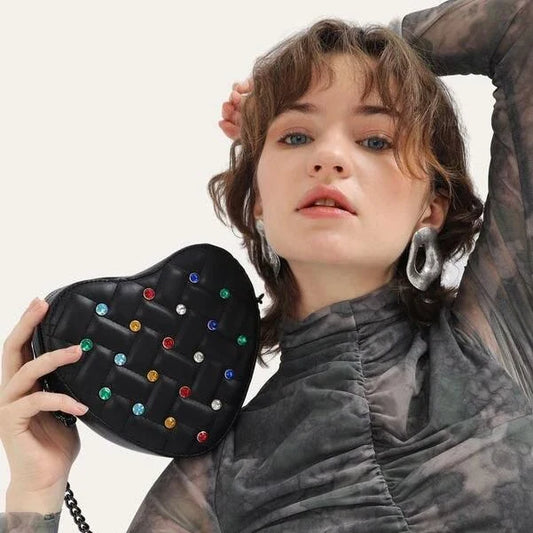 A stylish heart-shaped vegan leather crossbody bag with colourful rhinestone detailing, a versatile and fashionable accessory.