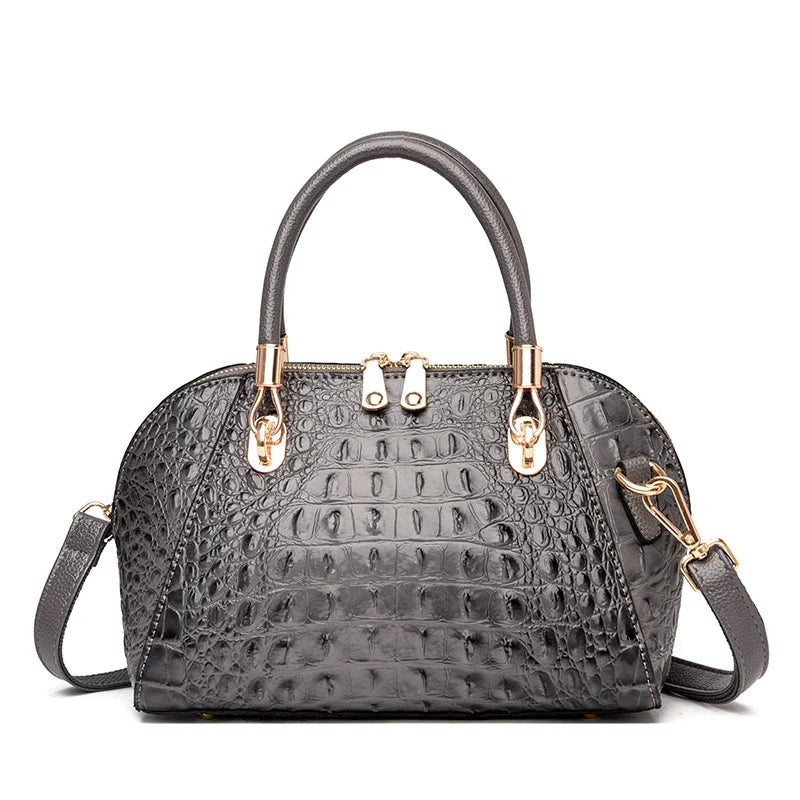 Premium leather one-shoulder messenger bag in various colours, featuring a sleek, shell-inspired silhouette and multiple internal pockets for organisation.