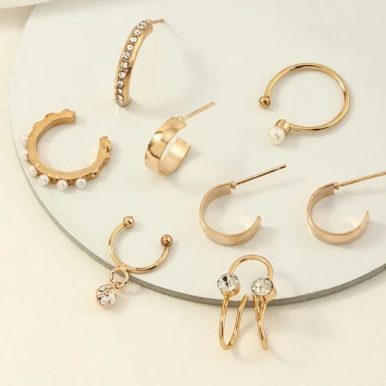 A set of 8 sophisticated gold-toned pearl stud earrings with unique, eye-catching designs