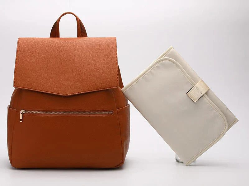 A stylish and practical PU leather mummy bag with a large capacity, multiple pockets, and included accessories like a changing pad and stroller hooks.