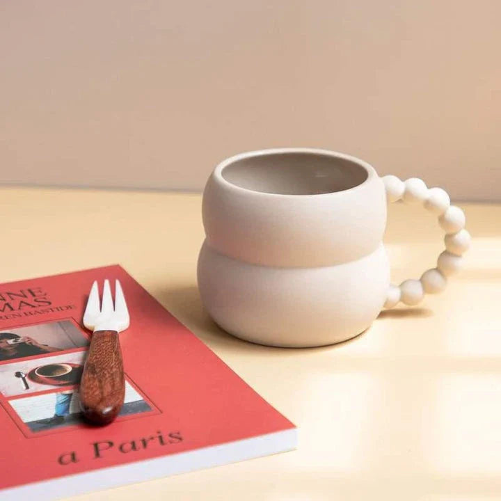 Handmade ceramic mug in beige and blue Nordic-inspired design, with a comfortable handle for enjoying hot or cold beverages.