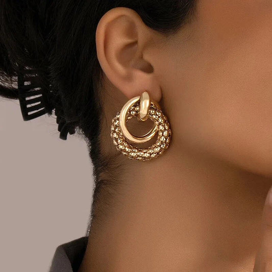 Exquisite gold twist dangle earrings with an intricate geometric design, a bold statement of modern elegance for fashion-forward women.