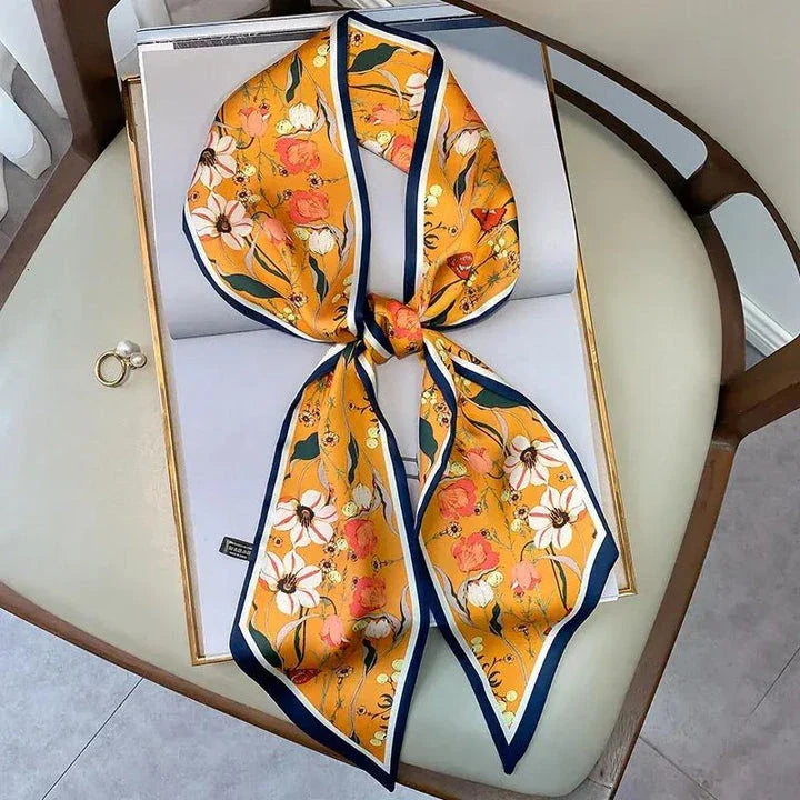 A vibrant floral-patterned silk-feel long scarf that can be worn as a neck accessory, hair tie, or wrist adornment for all occasions.
