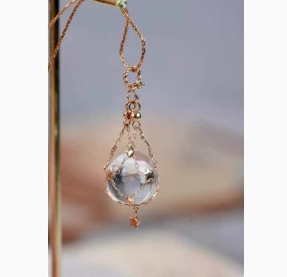 Exquisite 18K gold necklace with a delicate net pocket, inlaid gem, and iridescent shell beads