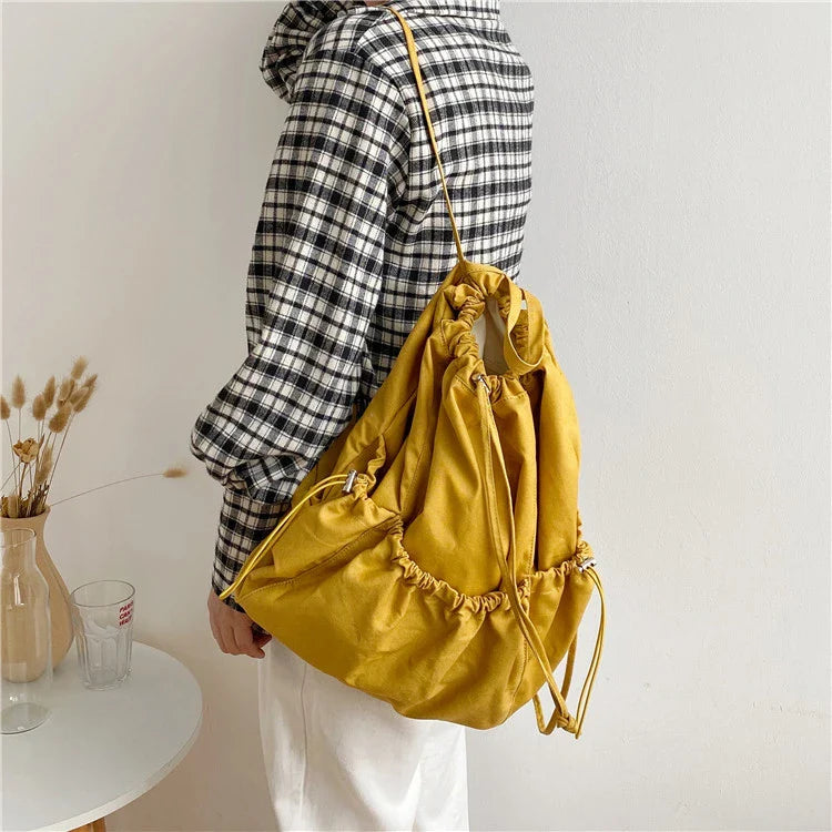 A stylish drawstring bucket bag in white, black, or brown colour options, featuring a spacious interior and adjustable closure for modern British women.