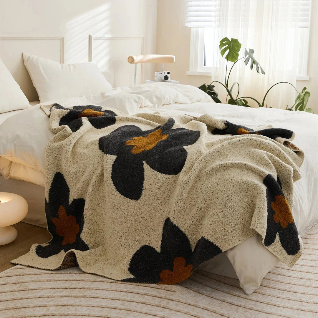 Cosy floral knitted throw blanket in red, grey, and orange colours for year-round comfort and style