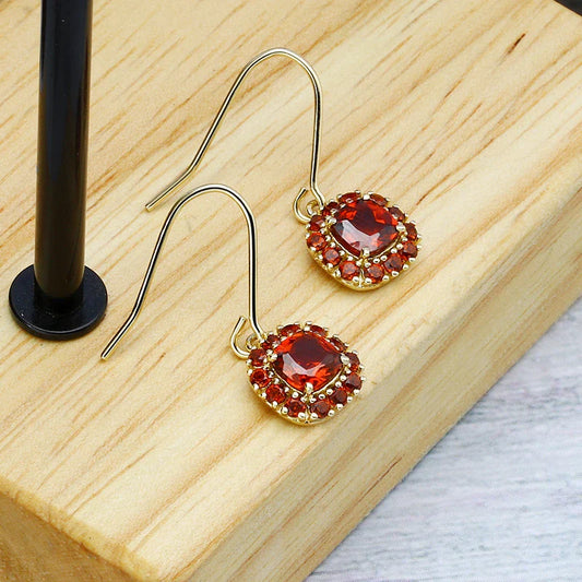 A pair of elegant red pomegranate-inspired earrings with a silver finish and geometric design, showcasing British style and sophistication.