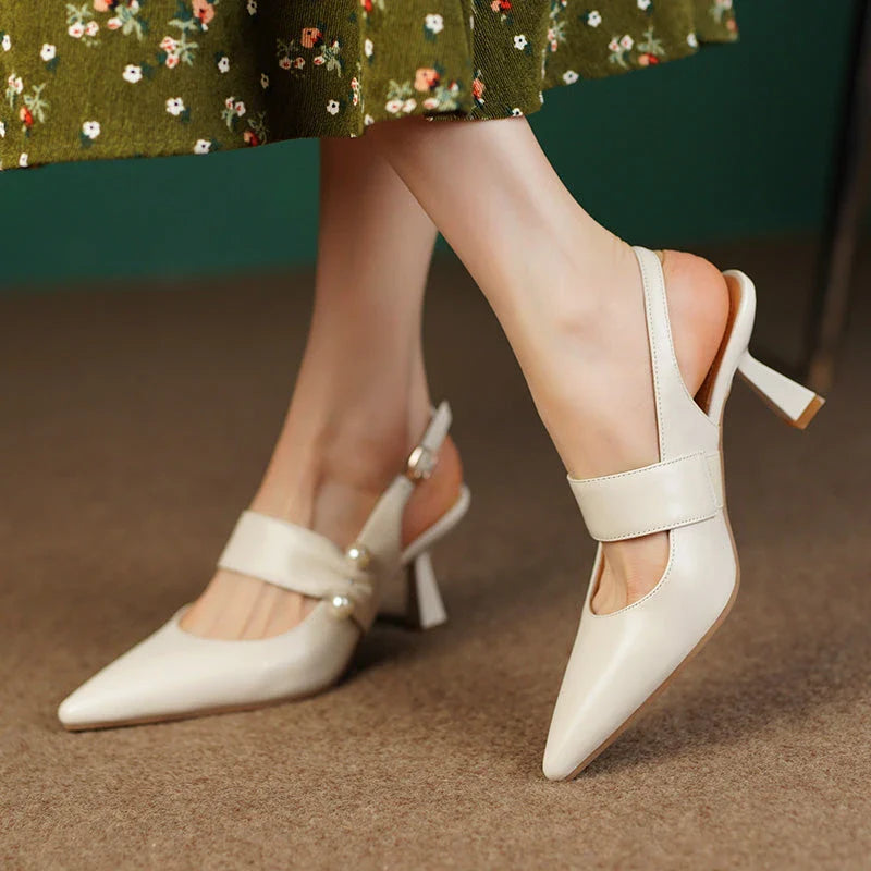 Pair of white high heel sandals with pearl embellishments, showcasing a unique and fashionable design