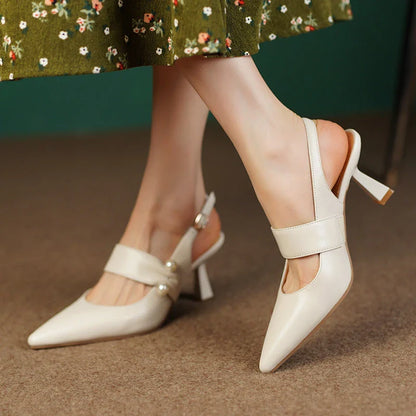 Pair of white high heel sandals with pearl embellishments, showcasing a unique and fashionable design
