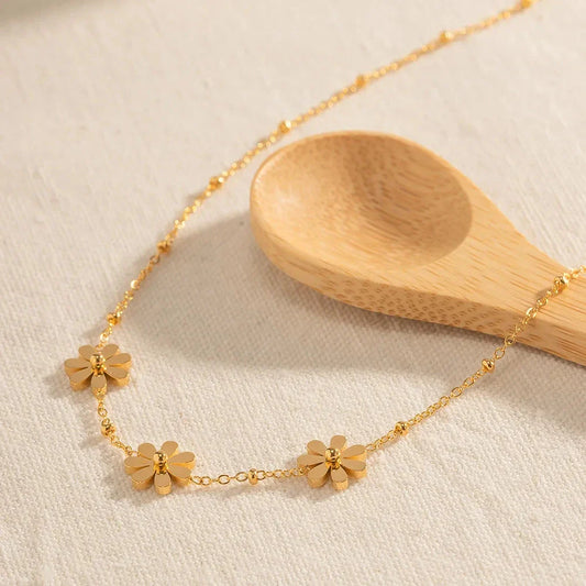 Exquisite 18-carat gold-plated necklace featuring three delicate daisy pendants on a stainless steel chain, embodying timeless British elegance and sophistication.