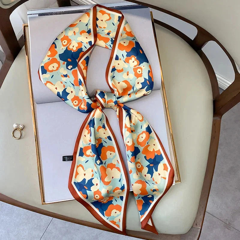A vibrant floral-patterned silk-feel long scarf that can be worn as a neck accessory, hair tie, or wrist adornment for all occasions.