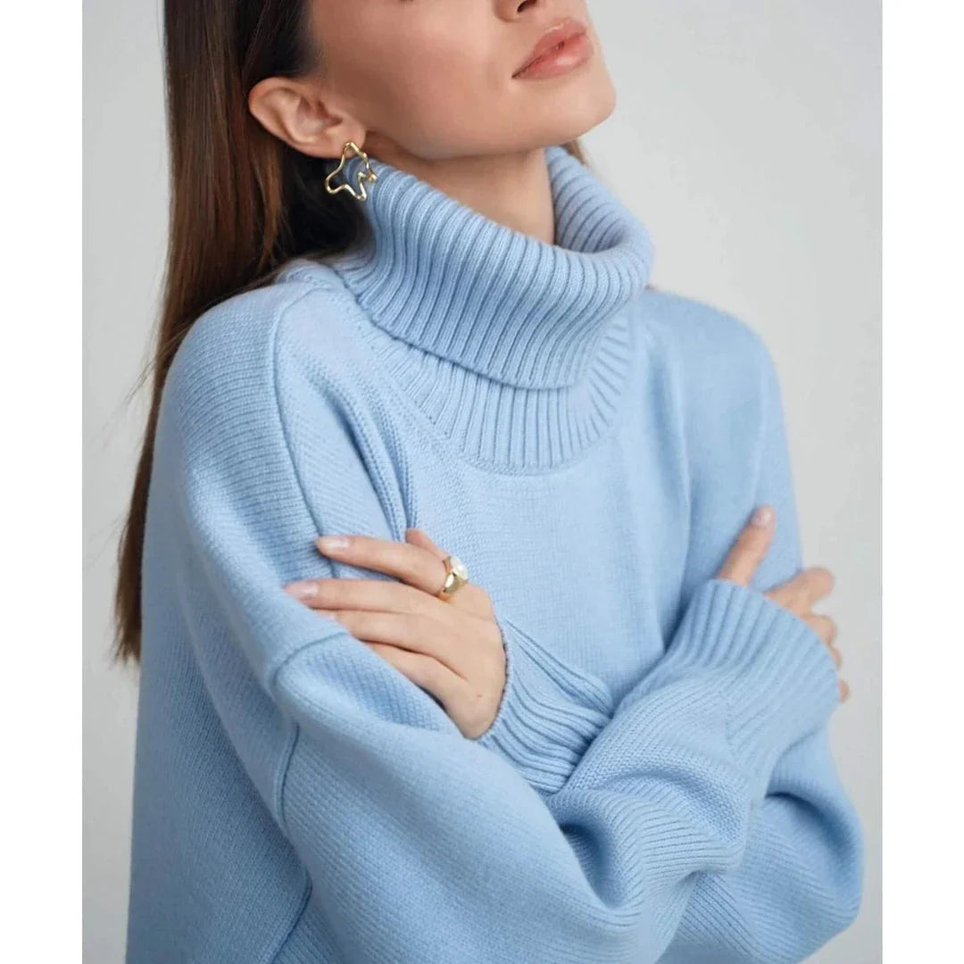 Cosy oversized knitted pullover in blue, featuring a classic turtleneck collar and drop-shoulder silhouette for maximum comfort and style.