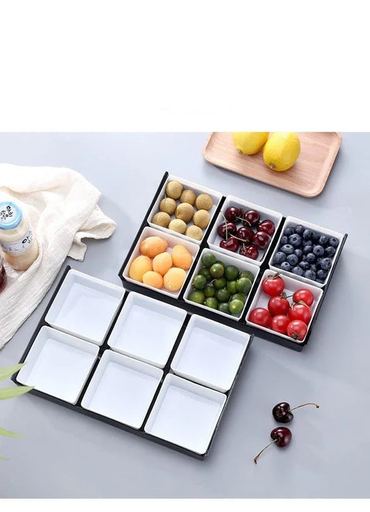 Premium British plastic snack trays in a variety of colours, including clear, white, and grey, with a black, white, or natural wood pallet for storage and display.