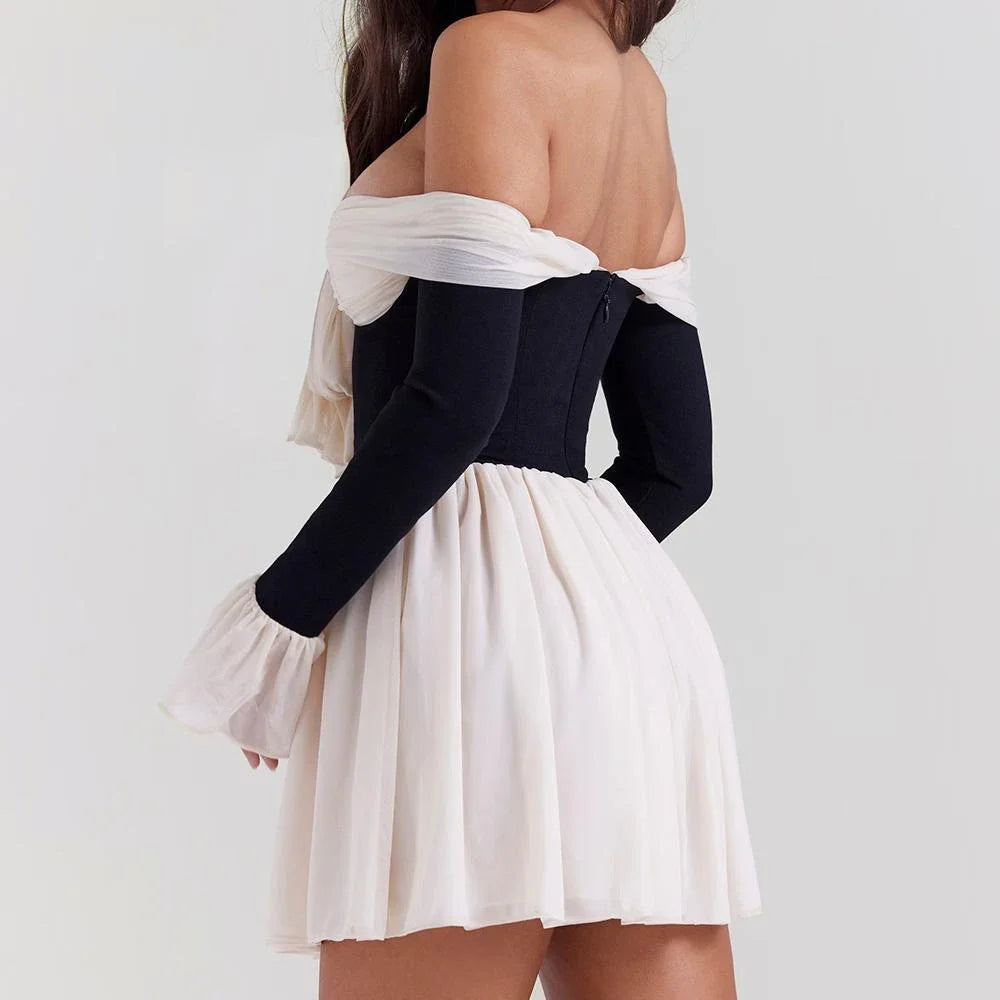 A woman wearing an elegant strapless and backless mini dress with flare sleeves, posing confidently in a party setting.