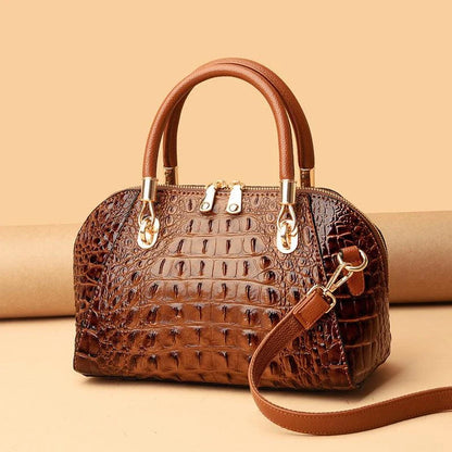 Premium leather one-shoulder messenger bag in various colours, featuring a sleek, shell-inspired silhouette and multiple internal pockets for organisation.