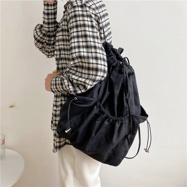 A stylish drawstring bucket bag in white, black, or brown colour options, featuring a spacious interior and adjustable closure for modern British women.