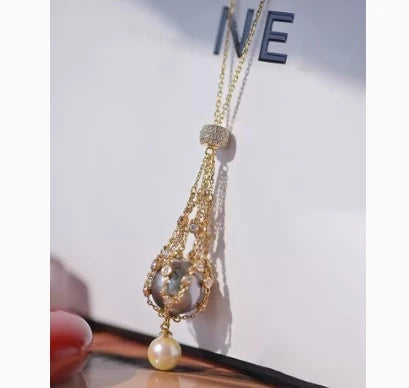 Exquisite 18K gold necklace with a delicate net pocket, inlaid gem, and iridescent shell beads