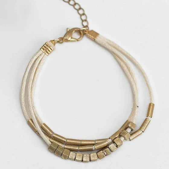 Stylish multilayered bracelet with beige leather ropes and gold-coloured beads, a modern and sophisticated accessory