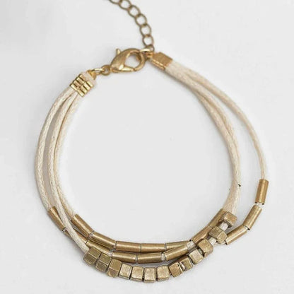 Stylish multilayered bracelet with beige leather ropes and gold-coloured beads, a modern and sophisticated accessory