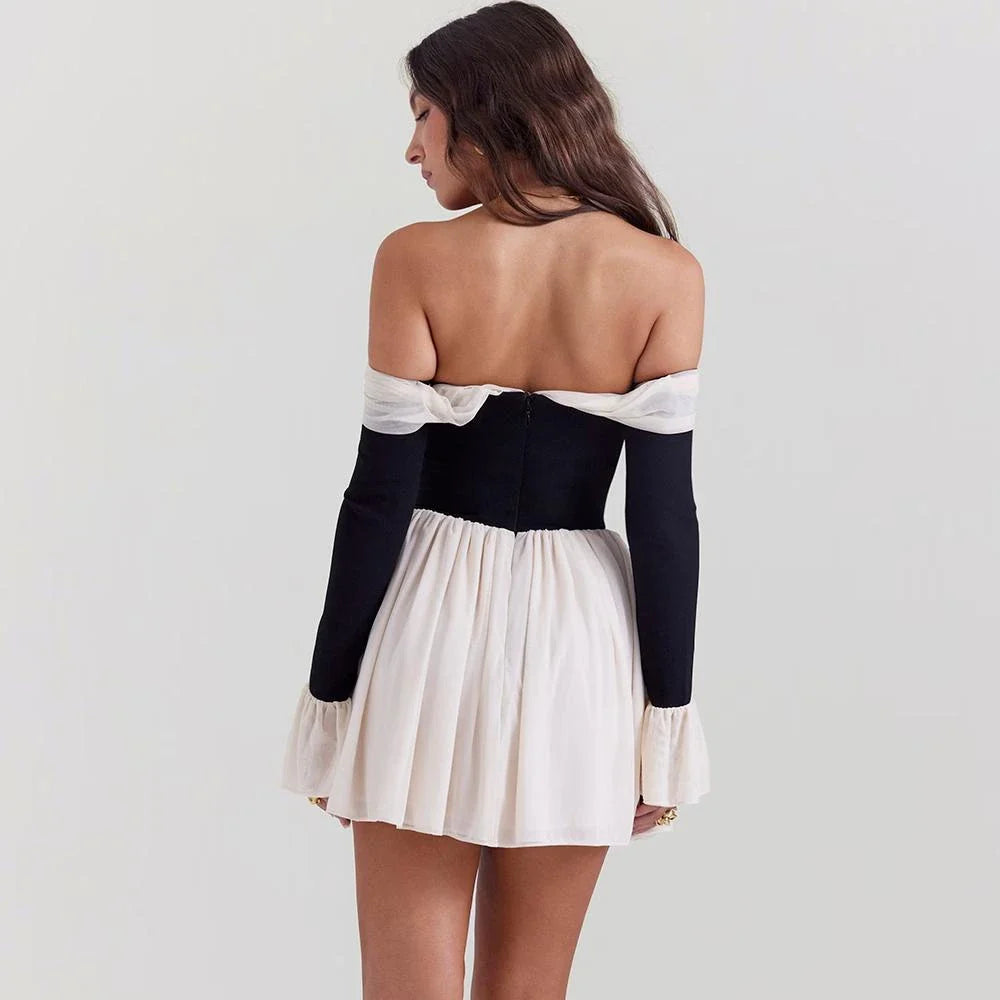 A woman wearing an elegant strapless and backless mini dress with flare sleeves, posing confidently in a party setting.