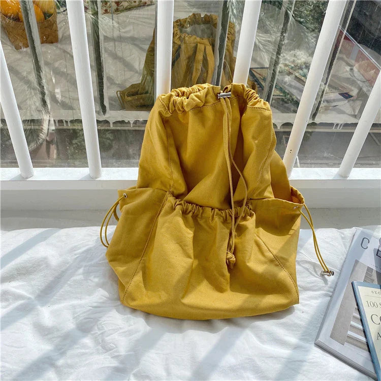 A stylish drawstring bucket bag in white, black, or brown colour options, featuring a spacious interior and adjustable closure for modern British women.