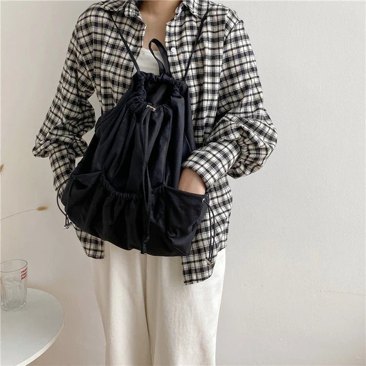 A stylish drawstring bucket bag in white, black, or brown colour options, featuring a spacious interior and adjustable closure for modern British women.