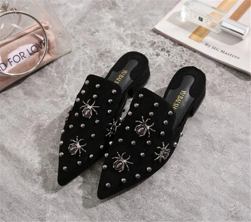 A pair of flat-bottomed, lazy half-slipper style sandals in a sleek, minimalist design with metal accents