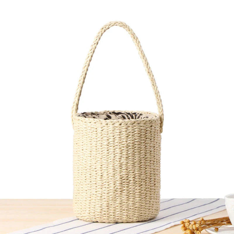 Elegant hand-crafted straw bucket bag in camel or beige, featuring a compact and lightweight design for versatile British summer style