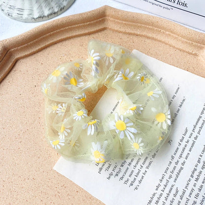A pair of white hair bands with vibrant, hand-embroidered daisy patterns, providing a stylish and comfortable accessory.