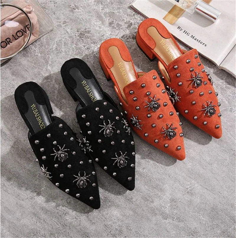A pair of flat-bottomed, lazy half-slipper style sandals in a sleek, minimalist design with metal accents