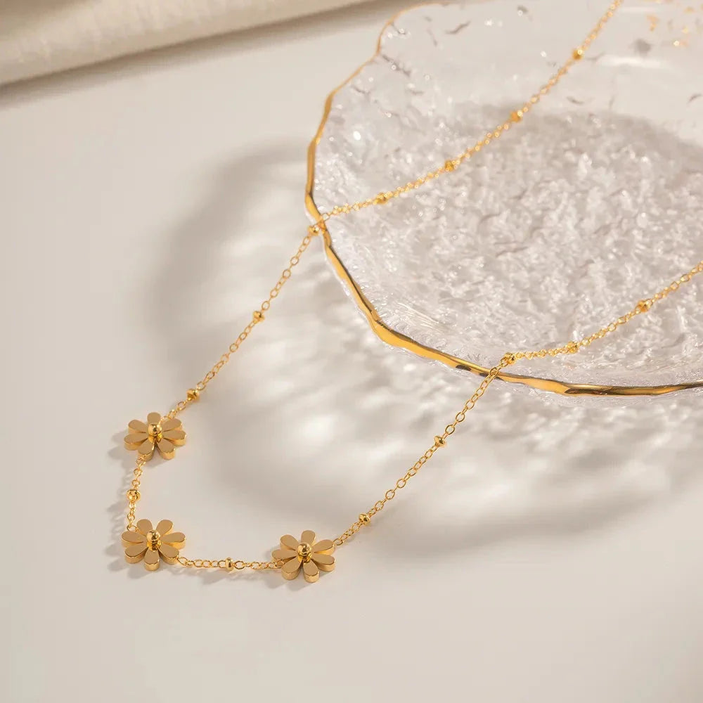 Exquisite 18-carat gold-plated necklace featuring three delicate daisy pendants on a stainless steel chain, embodying timeless British elegance and sophistication.