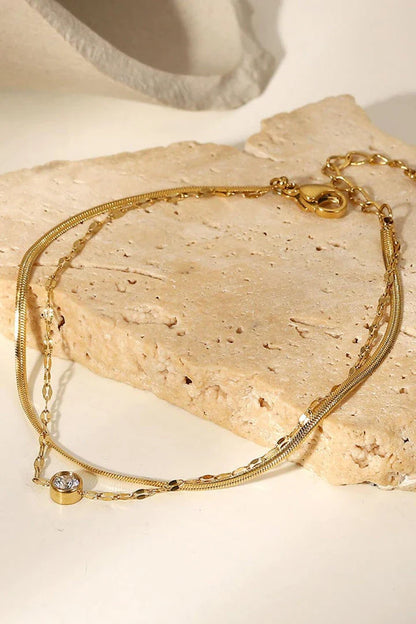 Close-up of a gold-coloured double-layered bracelet with sparkling rhinestones, on a white background.