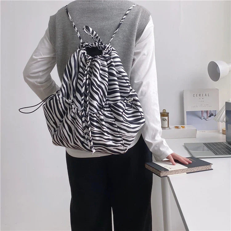 A stylish drawstring bucket bag in white, black, or brown colour options, featuring a spacious interior and adjustable closure for modern British women.