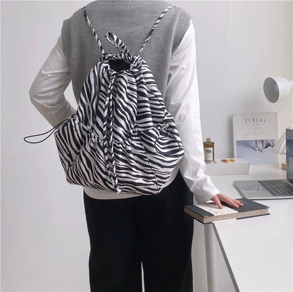 A stylish drawstring bucket bag in white, black, or brown colour options, featuring a spacious interior and adjustable closure for modern British women.