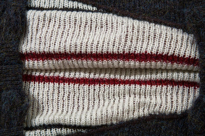 A cosy and stylish jumper featuring a patchwork design with contrasting stripes in a classic British colour palette.