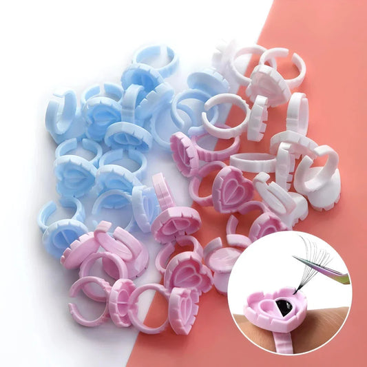 Heart-shaped disposable eyelash glue rings in blue, pink, and white colours