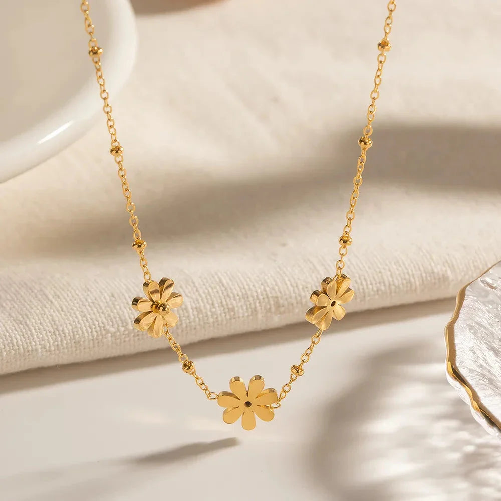 Exquisite 18-carat gold-plated necklace featuring three delicate daisy pendants on a stainless steel chain, embodying timeless British elegance and sophistication.