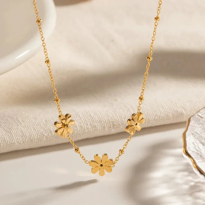 Exquisite 18-carat gold-plated necklace featuring three delicate daisy pendants on a stainless steel chain, embodying timeless British elegance and sophistication.