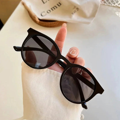 A pair of stylish, retro-inspired round sunglasses with a white frame, providing UV protection and a chic, contemporary look.