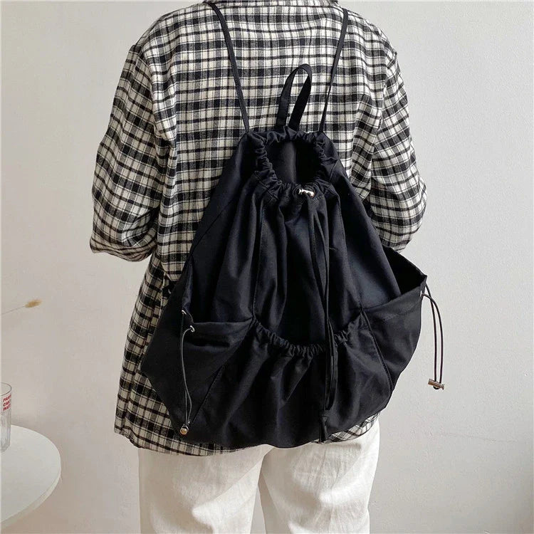 A stylish drawstring bucket bag in white, black, or brown colour options, featuring a spacious interior and adjustable closure for modern British women.