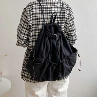 A stylish drawstring bucket bag in white, black, or brown colour options, featuring a spacious interior and adjustable closure for modern British women.