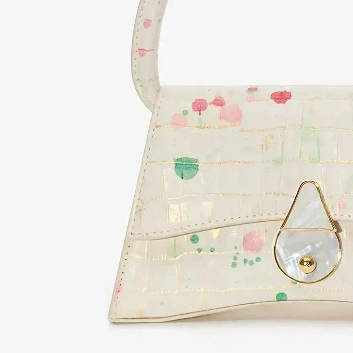 A stylish half-moon shaped genuine leather handbag with a decorative lock, showcasing premium British craftsmanship and timeless elegance.